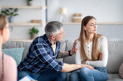 Mature married man supporting his depressed wife on consultation with psychologist at office. Family therapy concept