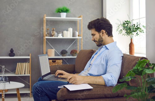 Millennial Hispanic man sit on sofa study online on laptop take course or training. Successful young Latin businessman work on computer, consult client customer. Technology, communication concept.