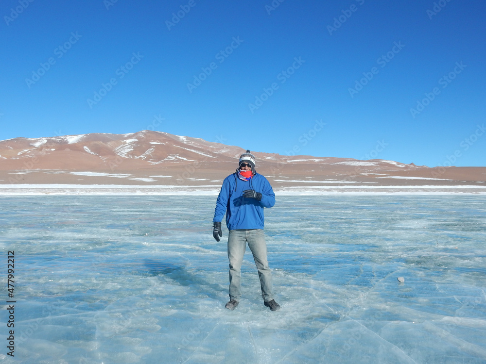 Tourist walking over frozen lagoon in Atacama Desert
