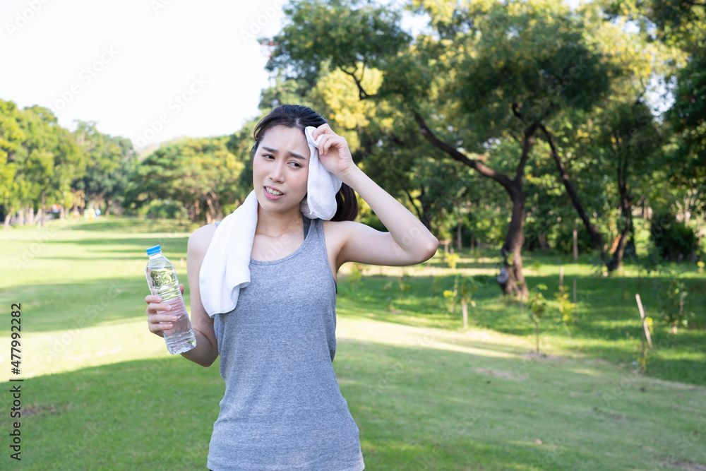 Female exercise and drink water. Beautiful girl in sportswear drinks water from a bottle during break. Young beautiful woman drinks water from a bottle in summer green park. Woman takes a break.