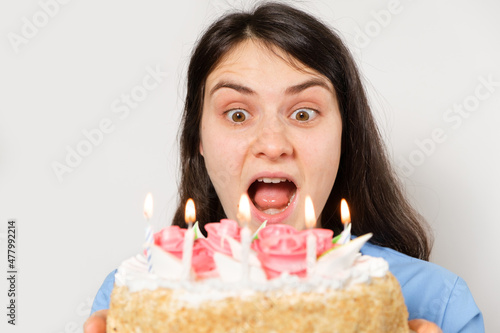 A woman doctor in a blue uniform holds a birthday cake with candles and smiles.