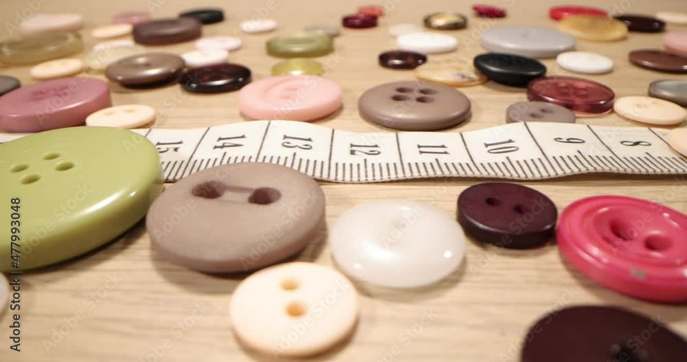 Buttons, needles, pins, spools and tailor's tape on wooden desk , close up. Fashion designer desk with equipment, tailoring and sewing workshop concept. 4k Buttons, needles, pins, spools and tailor's tape on wooden desk , close up. Fashion designer desk with equipment, tailoring and sewing workshop concept. 4k