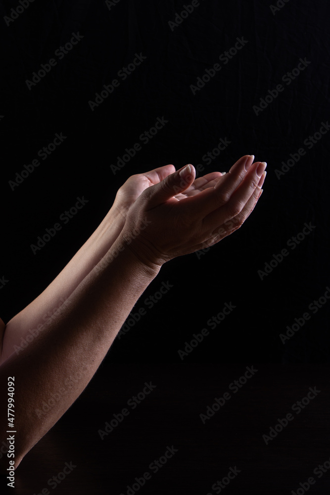Fototapeta premium Women's hands express confusion, loss. Plea. The concept of expressing emotions with your hands. Low key. Vertical frame