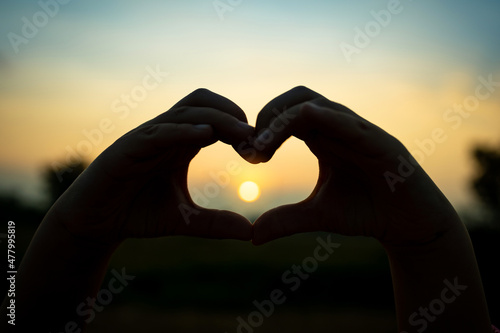 Hand of heart for concept of love. Silhouette symbolic with glare of sunset.