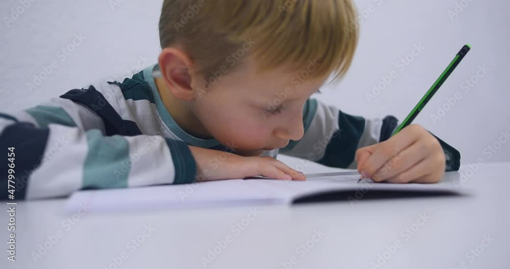 School boy practicing writing the alphabet at home. Boy child kid writing. Homework. School boy practicing writing the alphabet at home. Boy child kid writing. Homework.
