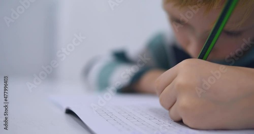 School boy practicing writing the alphabet at home. Boy child kid writing. Homework.