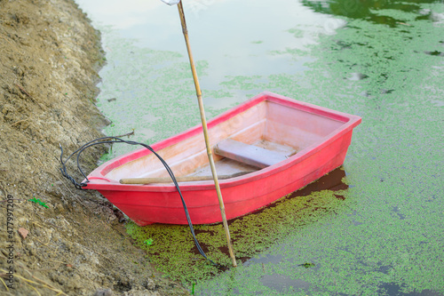 A small red fiberglass boat floats on the bank of the garden