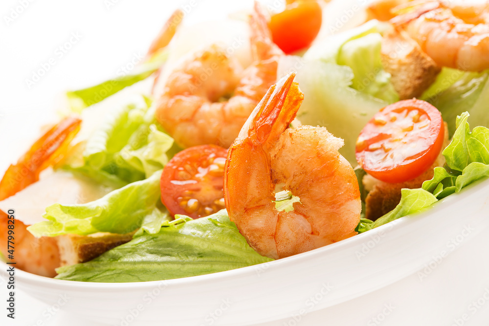 Caesar salad with fresh leaves, shrimp, cherry tomatoes in a plate isolated on a white background. Caesar salad with fresh leaves, shrimp, cherry tomatoes in a plate isolated on a white background.