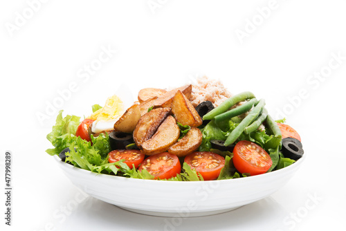A plate of nicoise salad with tuna and potatoes isolated on a white background