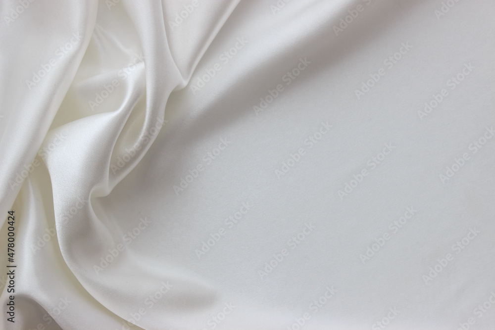 White silk fabric background with copy space. Abstract smooth elegant texture for design. Flowing satin waves.
