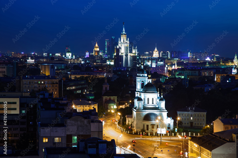 Fototapeta premium Deep blue saturated night sky with nightlights in the city panorama. Illuminated buildings and Silhouette of town. Moscow