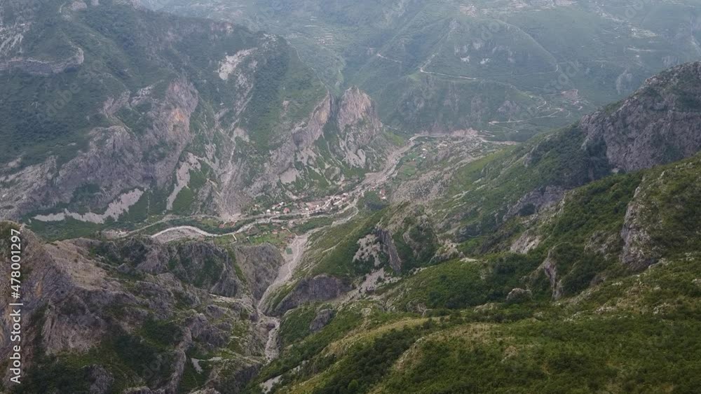 Bird's eye view of a small settlement in a mountain valley. Huge mountains around the valley. Aerial view of Montenegro mountains. Grlo Sokolovo Bird's eye view of a small settlement in a mountain valley. Huge mountains around the valley. Aerial view of Montenegro mountains. Grlo Sokolovo