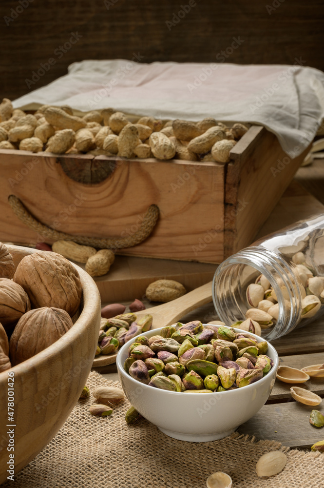 Different nuts and bowls closeup on a wooden table and brown background. Peanut, nut, cashew, almond, hazelnut, pistachio