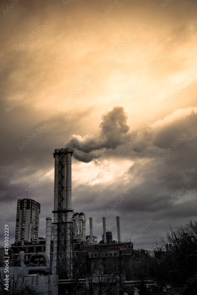 The smoking chimney of a large thermal power plant. Working plant against the background of the cloudy sky. The building of the old thermal power station under gloomy clouds