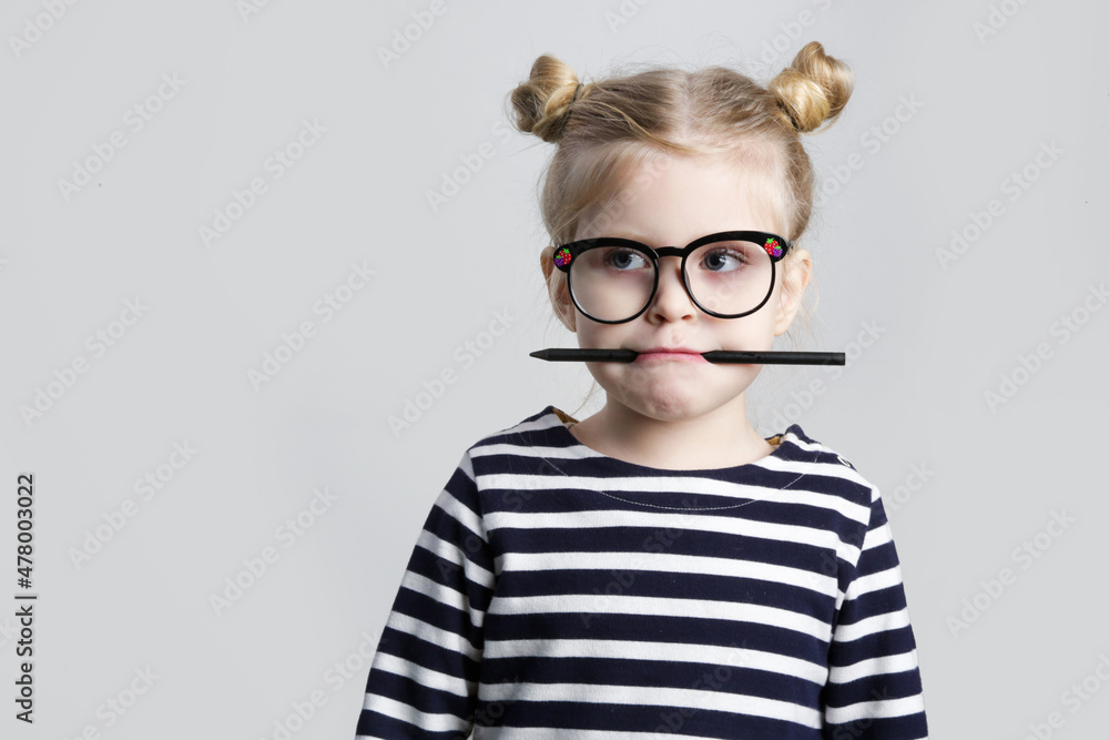 Portrait of cute little nerd child with pen in her mouth, studio shot. Portrait of cute little nerd child with pen in her mouth, studio shot.