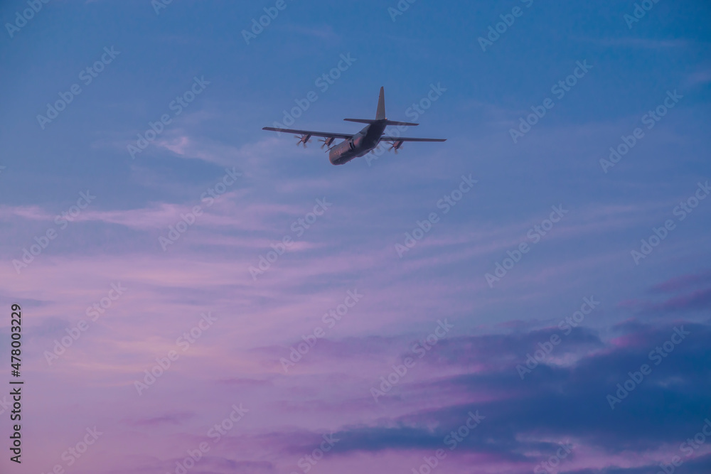 British RAF Hercules C-130J military air-to-air refuelling tanker aircraft in flight, illuminated by a pink sky sunset British RAF Hercules C-130J military air-to-air refuelling tanker aircraft in flight, illuminated by a pink sky sunset