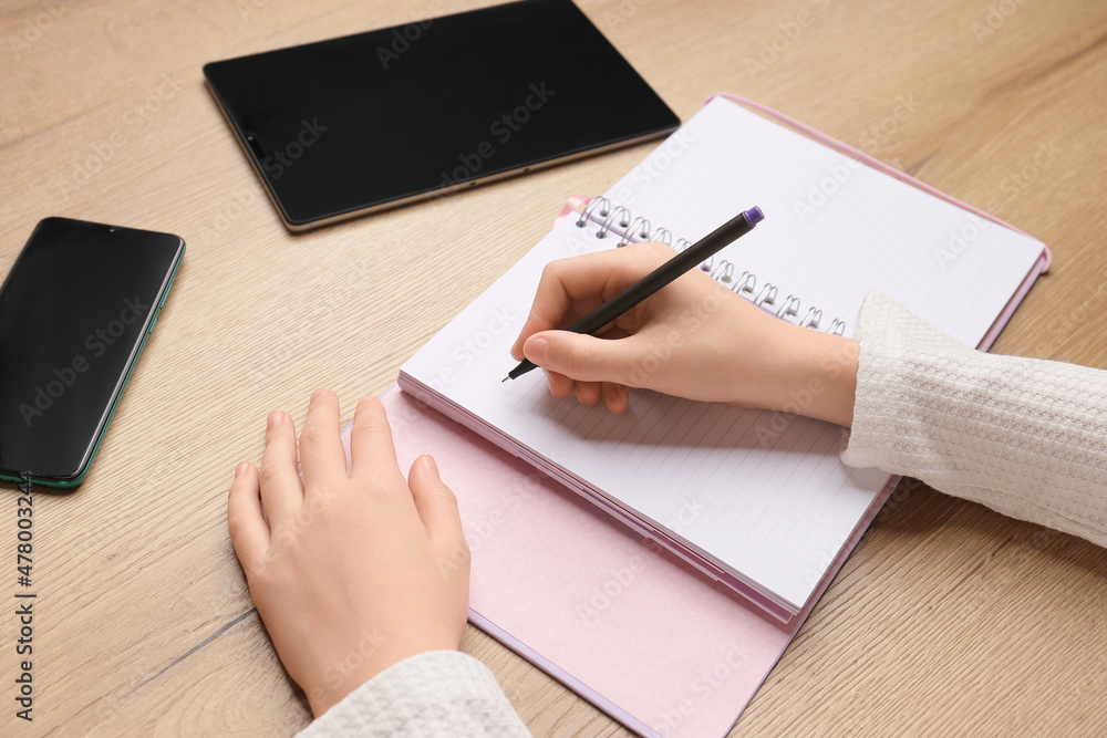 Fototapeta premium Children's hand writes in a notebook