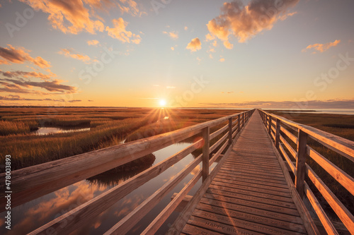 Grays Beach boardwalk in Yarmouth, Massachusetts during sunset with wooden pathway over marsh on coast