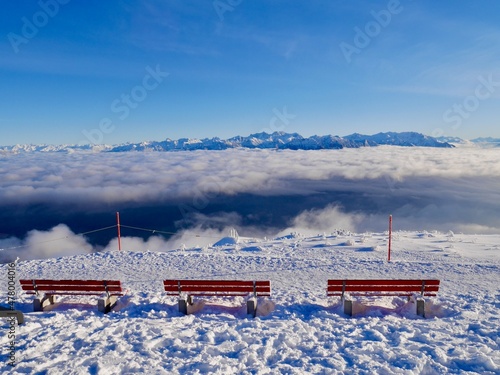 Red benches at mountain station of Hoher Kasten cable car with spectacular view of Austrian Alps in winter. Alpstein, Appenzell, Switzerland.