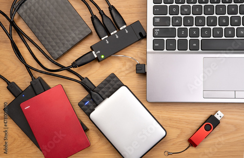 External hard drives connected to a laptop on wooden desk, top view photo