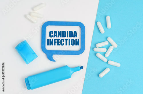 On a white and blue table are pills, a marker and a blue plaque with the inscription - Candida Infection