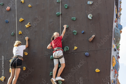 Two girls climb the climbing wall in the sports park climbing wall.