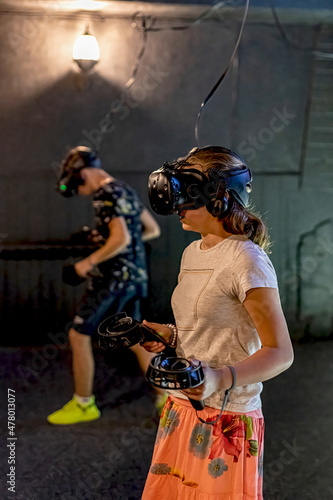 A guy and a girl in the computer room are playing games in a VR helmet.