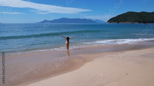 Brazilian woman in bikini on a deserted beach in Ubatuba, São Paulo, Brazil. Atlantic forest, yellow sand and clear sea water. Figueira beach paradise. © Pedro