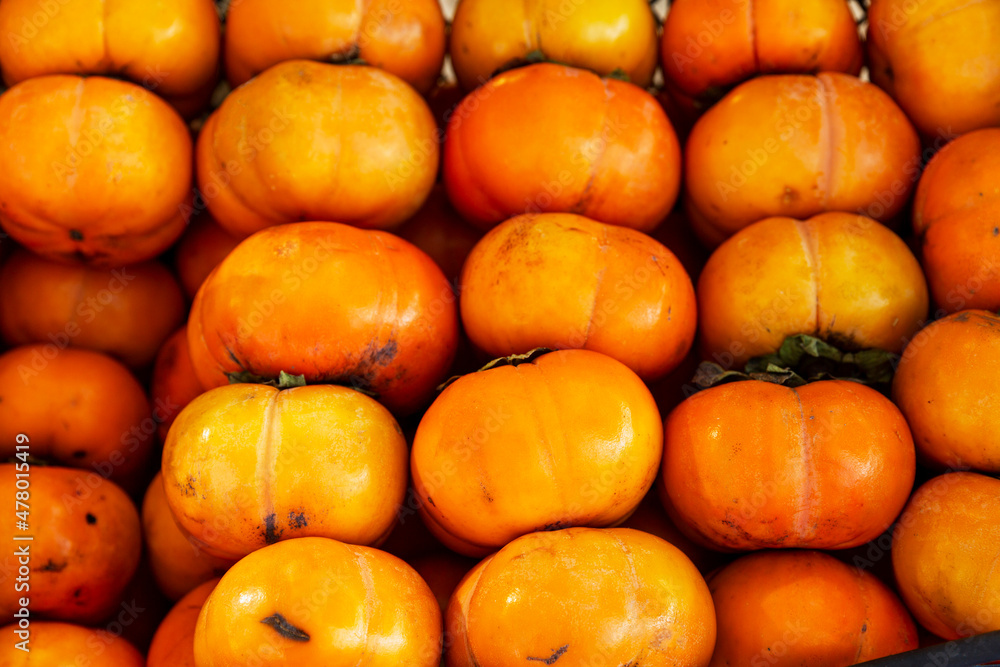 Fresh persimmon in a box at the market. Vitamins and healthy natural foods. Close-up.