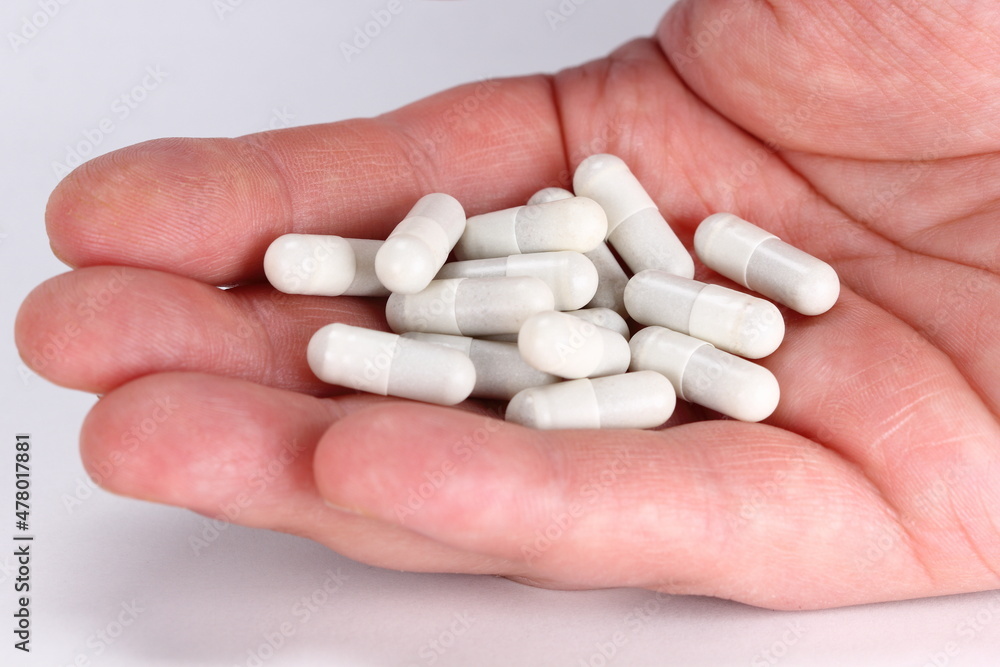 Man hand full of white tablets of medicine Man hand full of white tablets of medicine