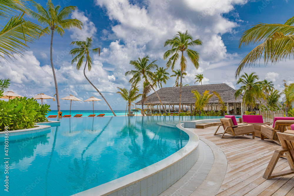 Fototapeta premium Amazing outdoor tourism landscape. Luxurious beach resort with swimming pool seaside beach chairs or loungers under umbrellas with palm trees and blue sky. Summer travel hotel and vacation background 