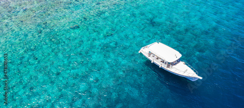 Luxury small yacht anchoring in shallow water. Aerial view of tropical island beach holiday yacht on blue reef ocean, outdoor sport, summer activity snorkeling, diving in exotic travel destination  © icemanphotos