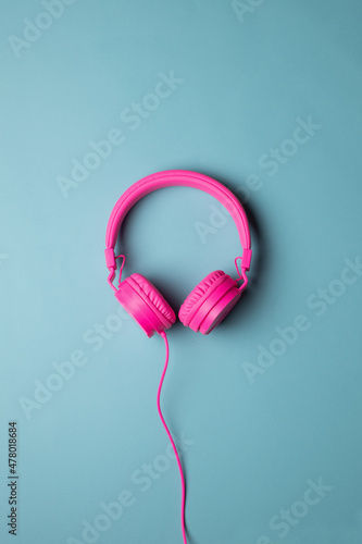 pink plastic earphones with cable placed in the center © Rufino