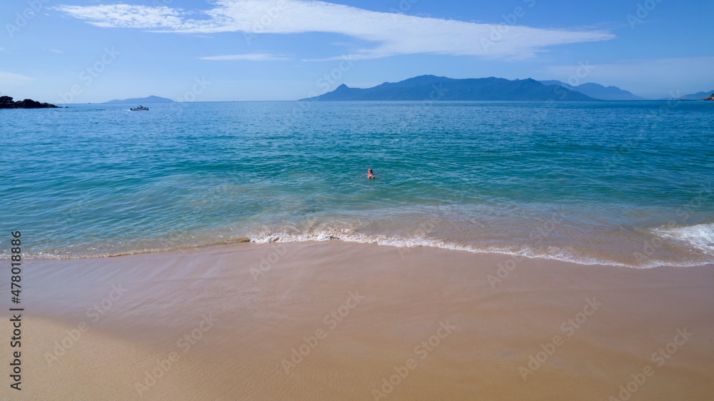 Fototapeta premium Brazilian woman in bikini on a deserted beach in Ubatuba, São Paulo, Brazil. Playing in the sea water Atlantic forest, yellow sand and clear sea water. Figueira beach paradise.