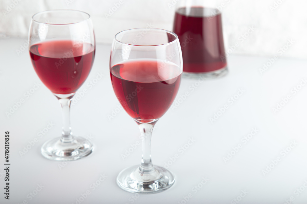 Closeup detail view of bowls of red wine and carafe, over white backdrop Closeup detail view of bowls of red wine and carafe, over white backdrop