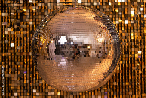 silver disco ball on a wall of sequins