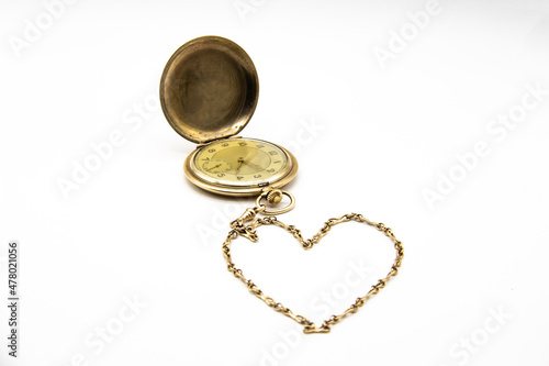 Vintage golden old pocket watch on white background. The chain lies in the form of a heart.