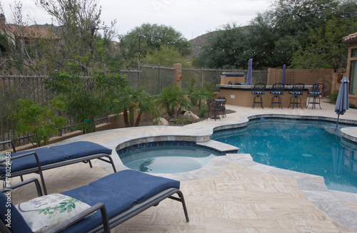 Blue lounge chairs on a travertine Tile pool deck.