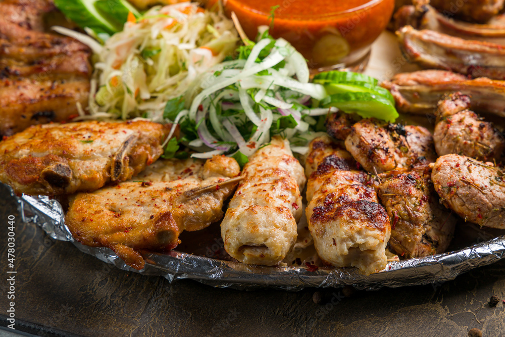 platter of different kebabs, lula kebab chicken, skewers of veal, onion, cabbage and tomato sauce macro close up