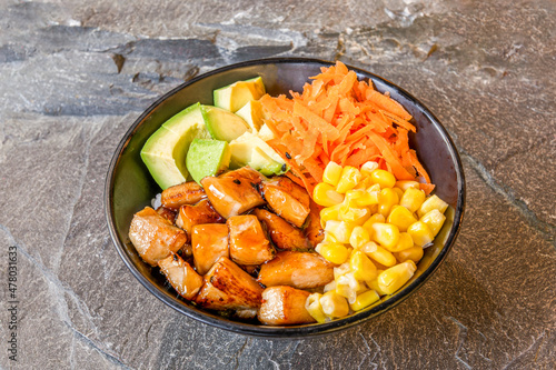 Poke bowl with ripe avocado, yakisoba chicken, sweet corn and grated carrot