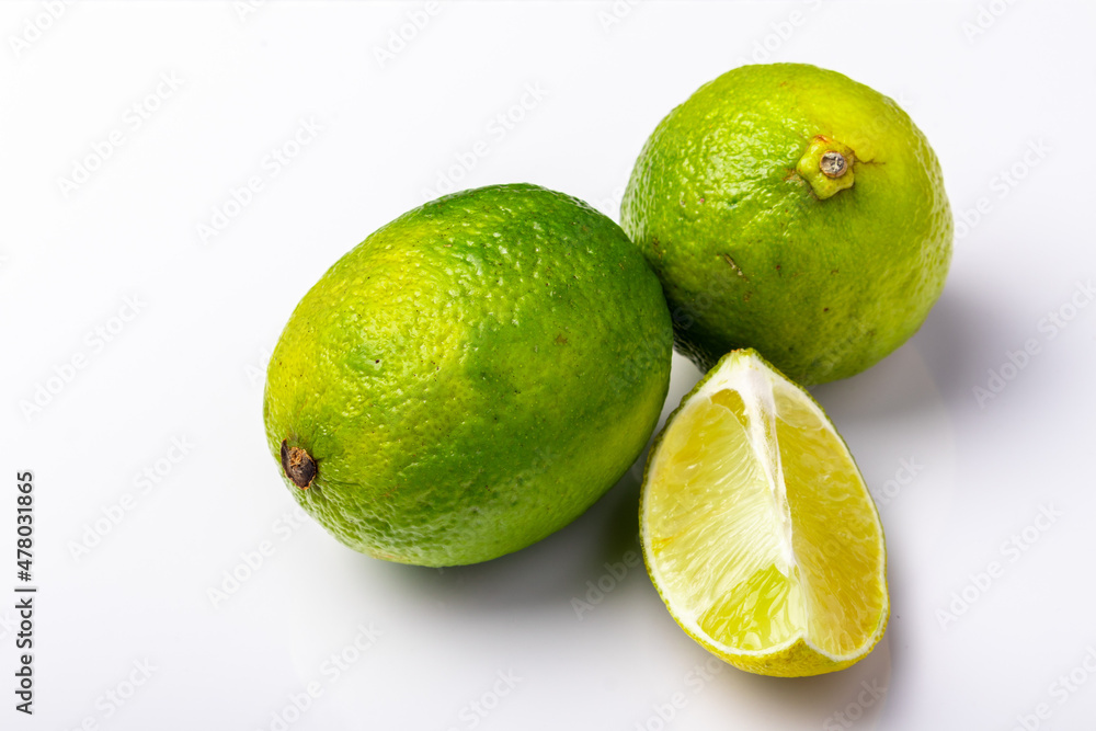 two whole and one cut limes on white background two whole and one cut limes on white background