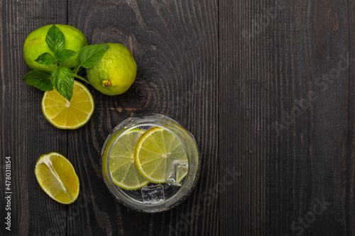 glass of sparkling mineral water with sliced lime on a wooden background top view