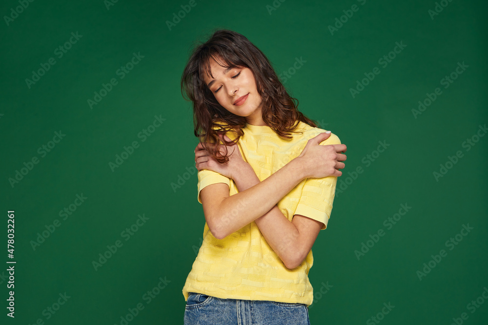 Pleased young girl embrace herself feeling self love and care on green background. Body acceptance, good self esteem Pleased young girl embrace herself feeling self love and care on green background. Body acceptance, good self esteem