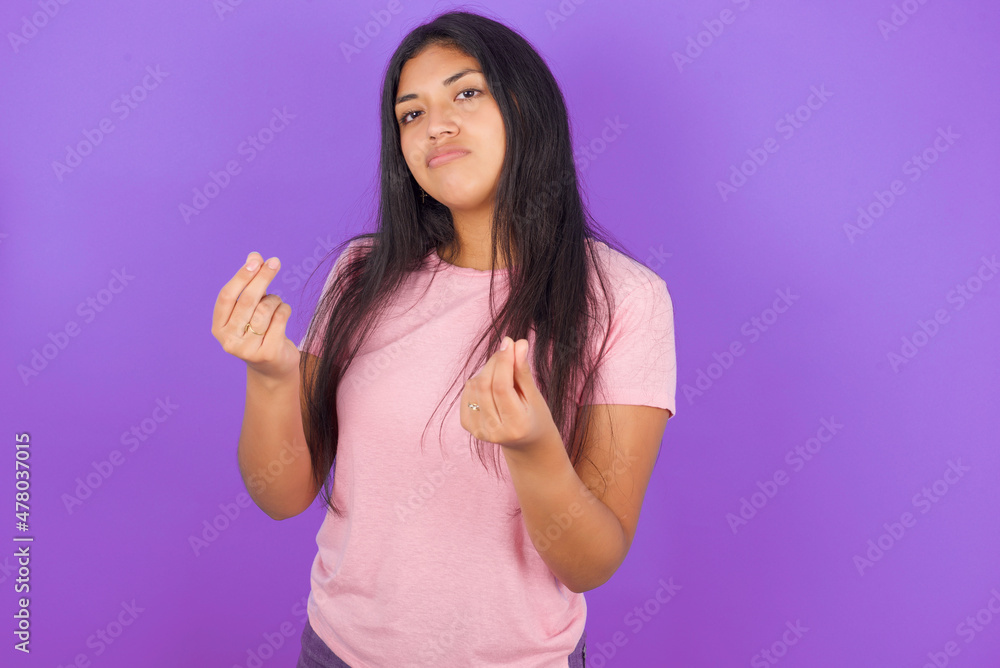 Hispanic brunette girl wearing pink t-shirt over purple background doing money gesture with hands, asking for salary payment, millionaire business Hispanic brunette girl wearing pink t-shirt over purple background doing money gesture with hands, asking for salary payment, millionaire business