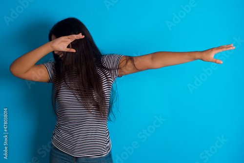Fototapeta Photo of funky hispanic girl wearing striped t-shirt standing over blue backgrou