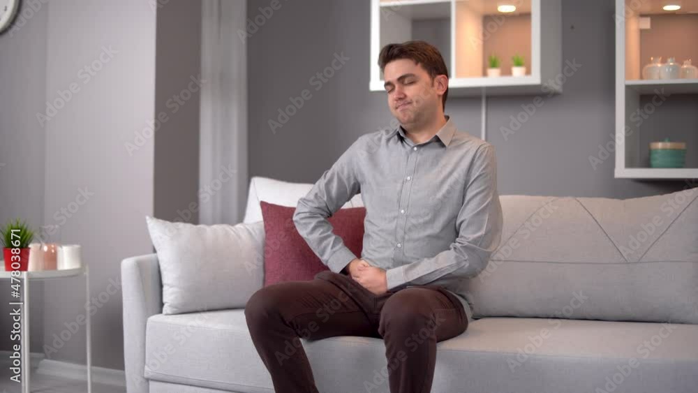 Abdominal pain in teenagers. The young man's stomach hurts. He sits slumped. Abdominal pain in teenagers. The young man's stomach hurts. He sits slumped.