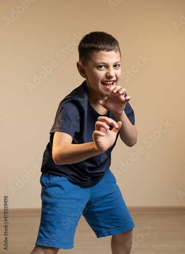 a boy in a blue t-shirt growls and holds his hands in front of him, depicts a tiger