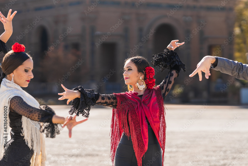 Three people dancing flamenco in traditional costumes in a square