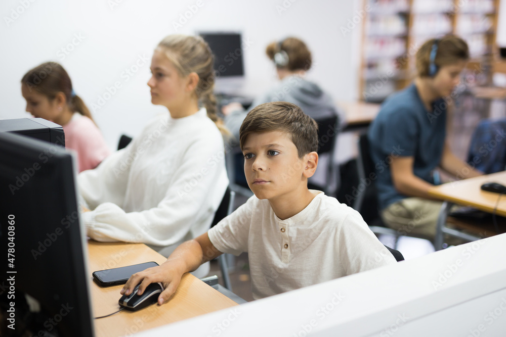 Preteen boy and girl learn to solve problems on computer in a school classroom