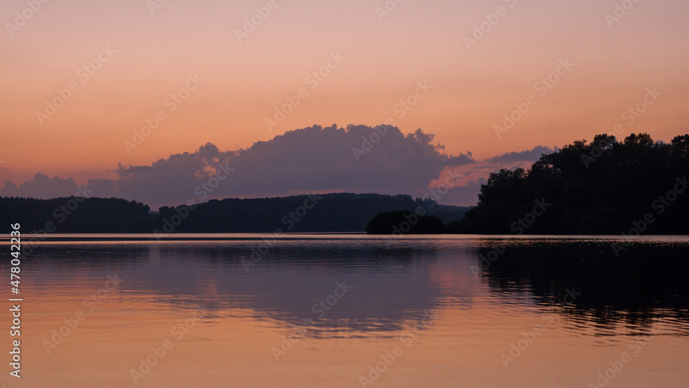 The reflections of trees on Lake Settons at sunset in Europe, France, Burgundy, Nievre, Morvan, in summer.